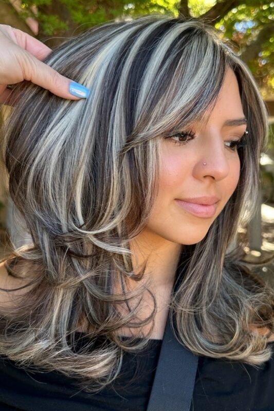 Woman with thick icy platinum highlights on black hair.