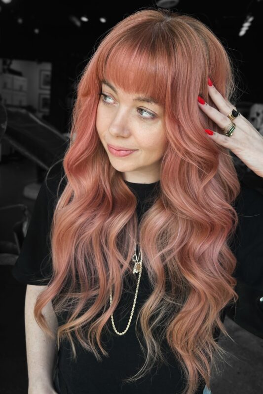 Mujer con cabello color melocotón dorado rosa.