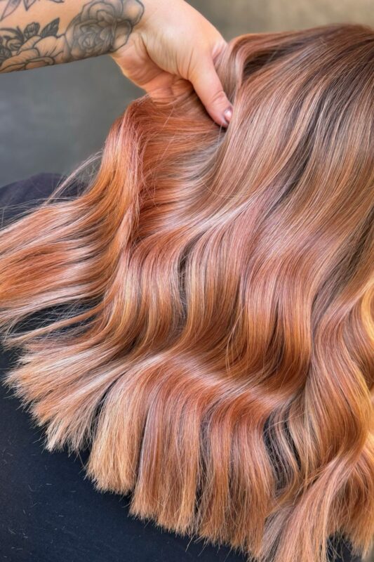 Woman with a rose gold peach strawberry blonde hair color.