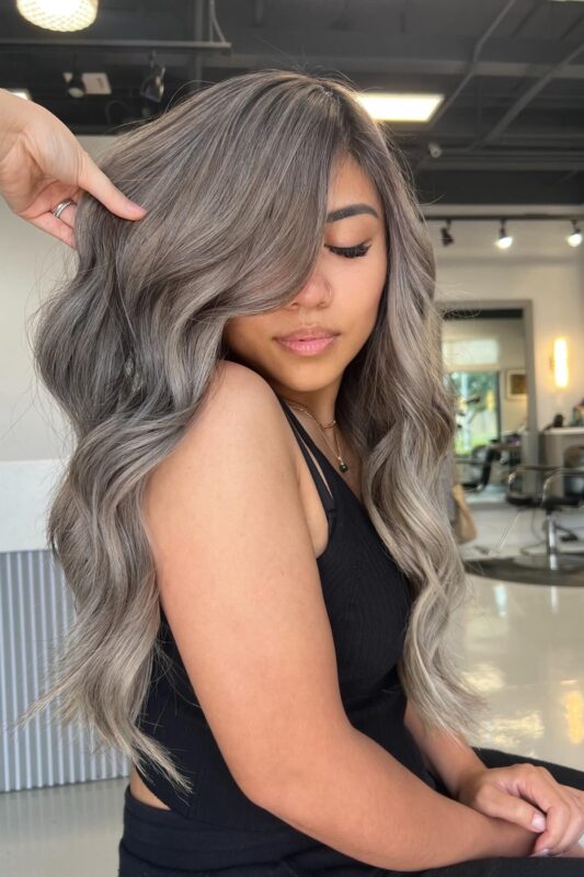 Woman with silver balayage on dark brown hair.