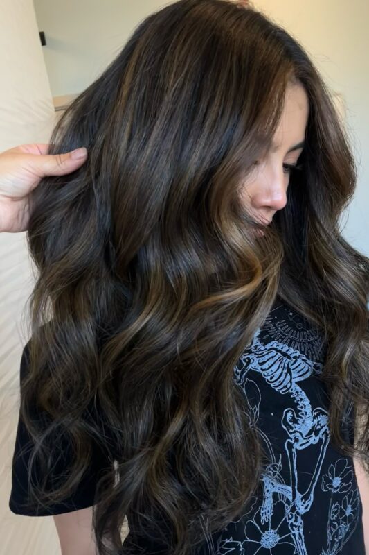 Woman with subtle, barely-there highlights on dark brown hair.