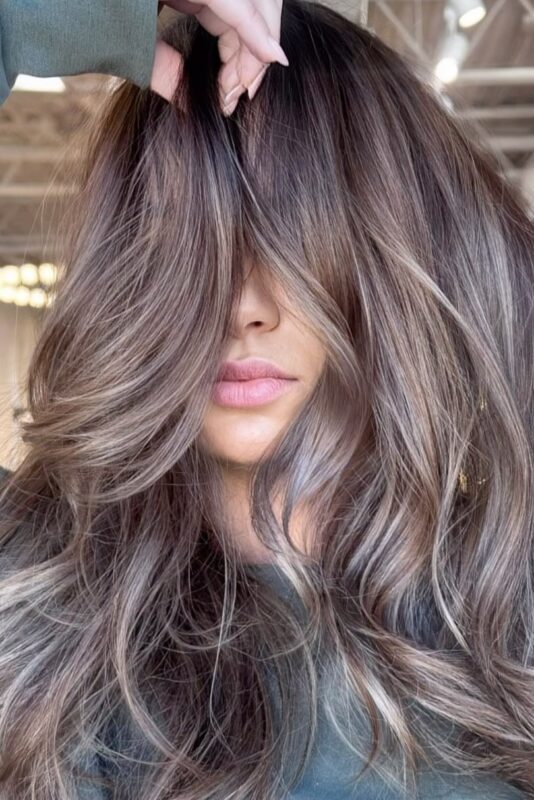 Woman with subtle, barely-there blonde balayage on medium brunette hair.