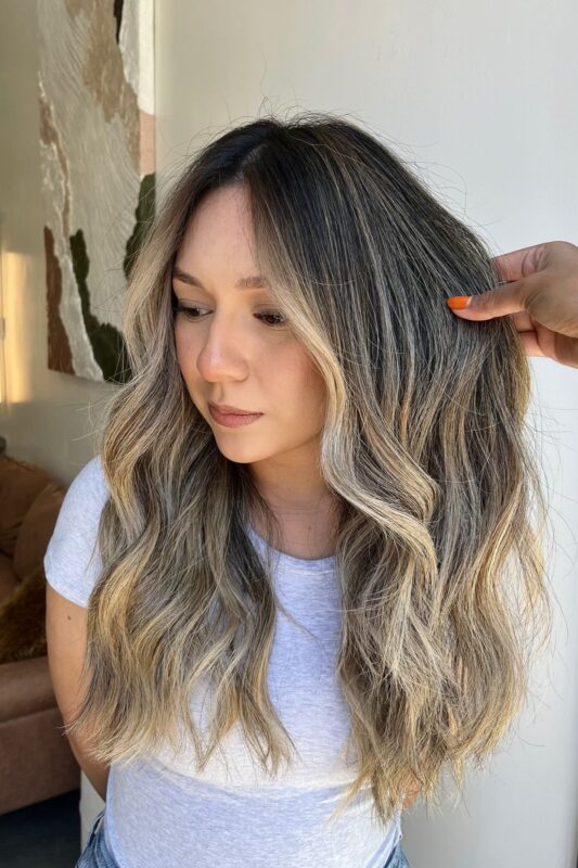 Woman with toasted blonde balayage on dark brown hair.