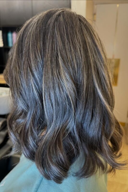 A seamless look achieved by blending gray hair with highlights and lowlights.