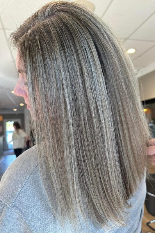 A hairstyle featuring blending grey hair with highlights and lowlights for a natural appearance.