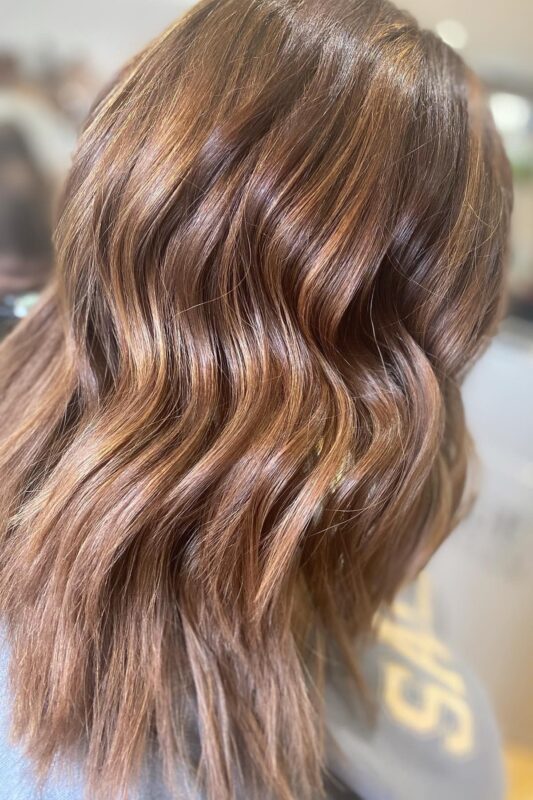 Woman with a chestnut balayage on her brown hair.