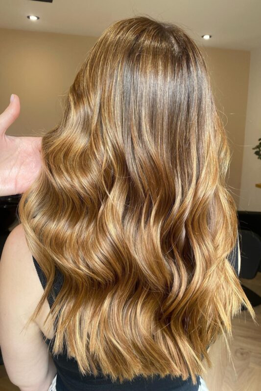 Woman with a golden blonde balayage on her brunette hair.