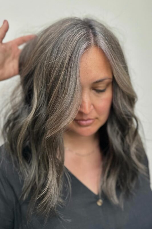 Graying brown hair enhanced with silver highlights for a soft blend.