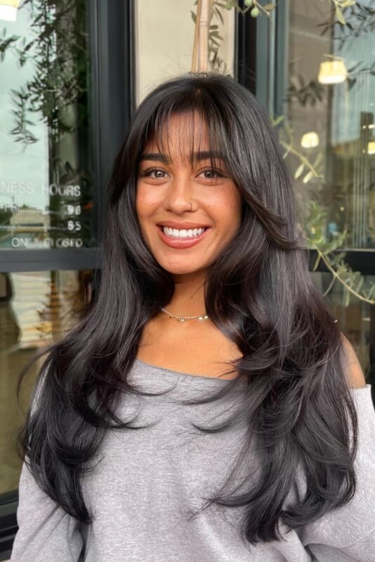 Woman with bangs and face-framing layers.