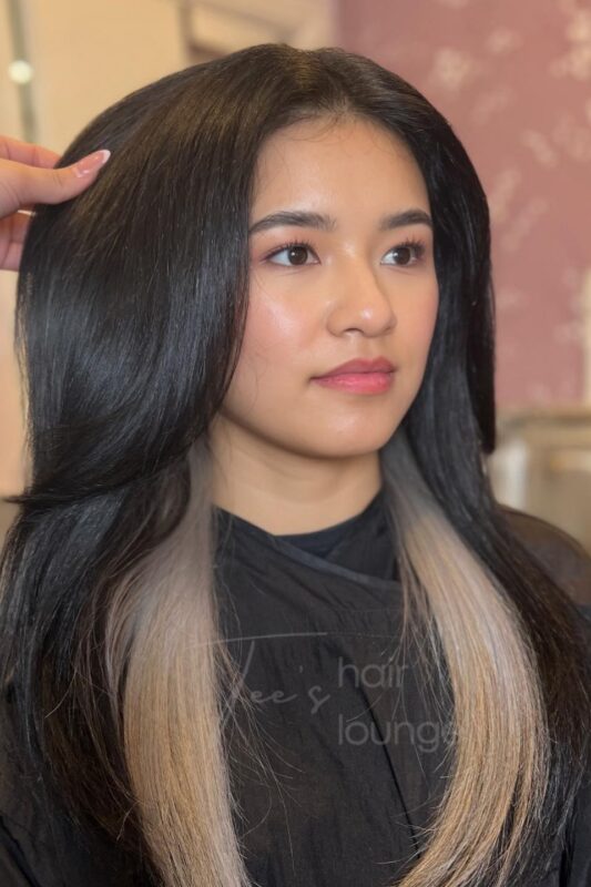 Woman with blonde peekaboo highlights on her brunette hair.