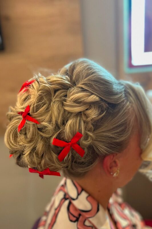 Woman with a braided crown Christmas hairstyle decorated with tiny red bows.