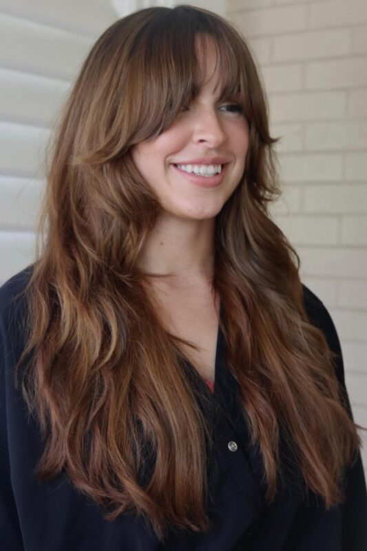 Woman with a face-framing layers and bangs haircut.