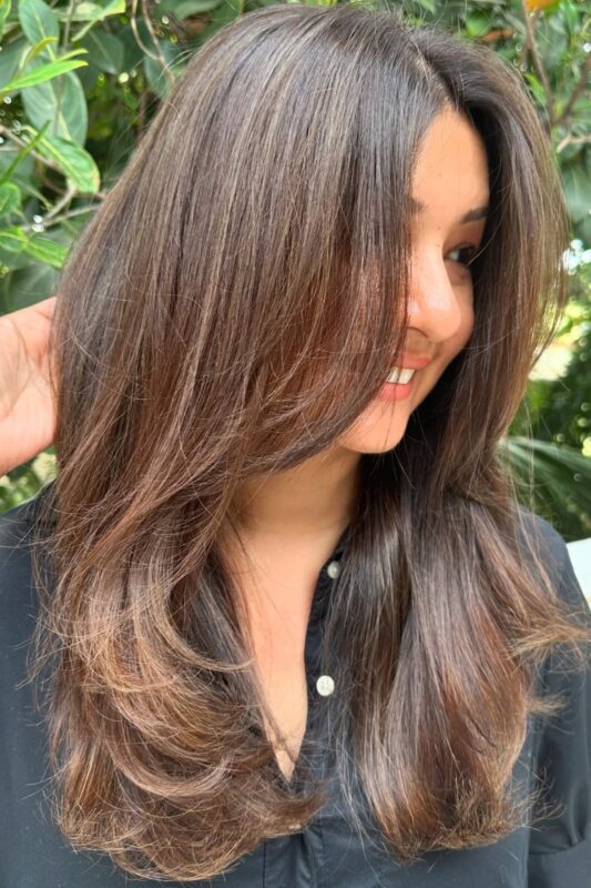 Woman with long hair styled with face-framing layers.