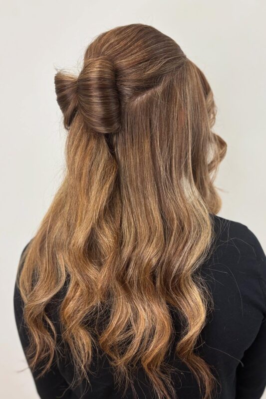 Woman with brunette hair styled in a festive bow.