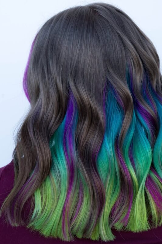 Woman with multi-color peekaboo highlights in her dark hair.