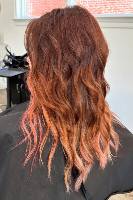 Woman with rose gold peekaboo highlights.