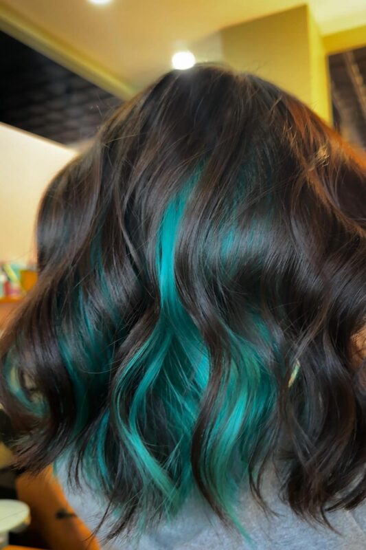 Woman with turquoise peekaboo highlights on her black hair.