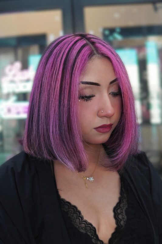 Woman with black hair and bright mauve pink streaks.