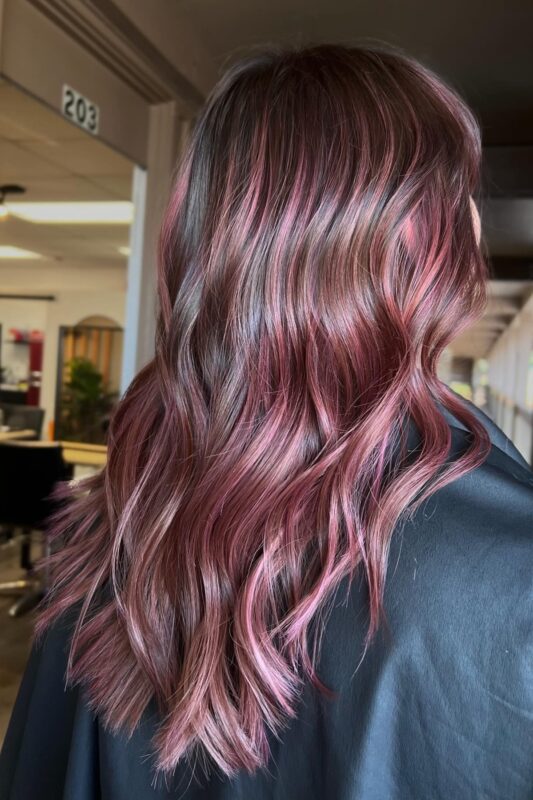 Woman with ash brown hair and light rose gold pink highlights.