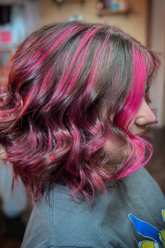 Woman with brown hair and fuchsia pink streaks.