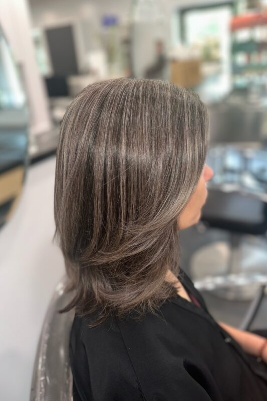 Brunette hair featuring warm-toned grey highlights for gray blending.