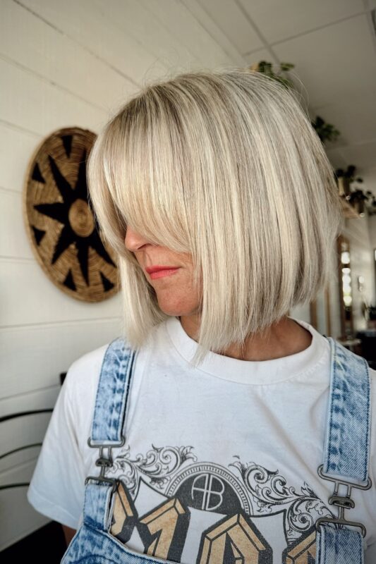 Woman with a chin-length blunt bob haircut and feathered bangs.