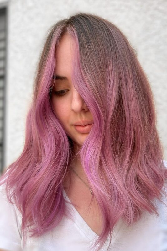 Woman with a dusty pink balayage and a money piece.