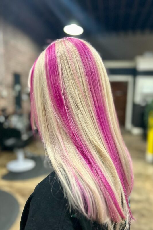 Woman with hot pink chunky highlights on her blonde hair.