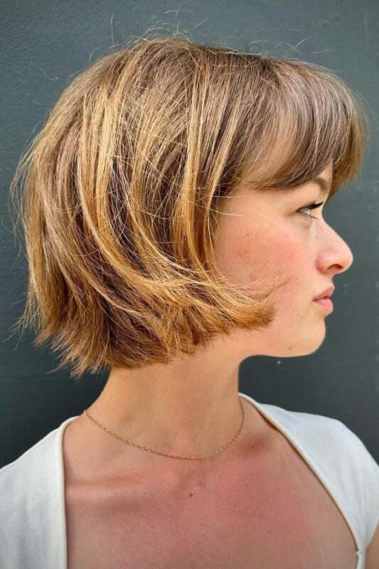 Woman with a layered French bob and bangs.