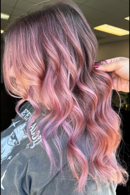 Woman with a pastel pink balayage on her dark hair.