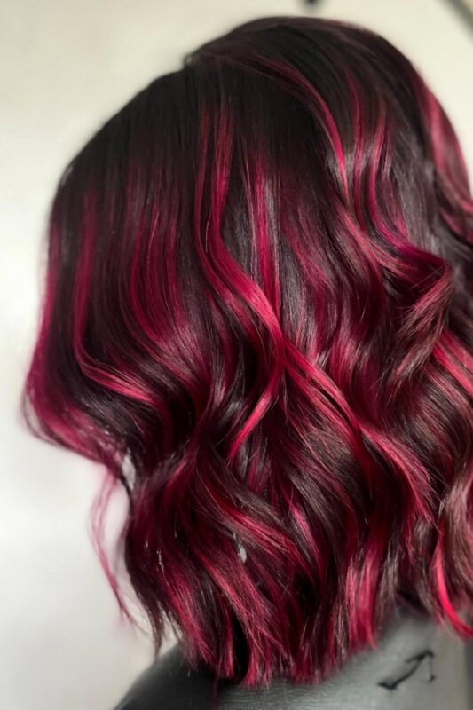 Woman with a neon pink balayage on her dark hair.