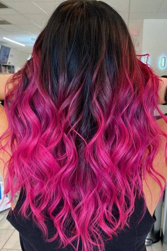 Woman with a vibrant pink balayage on her black hair.