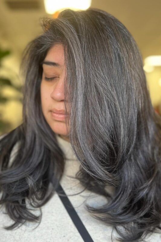 Dark brown hair accentuated with striking silver grey blending highlights.